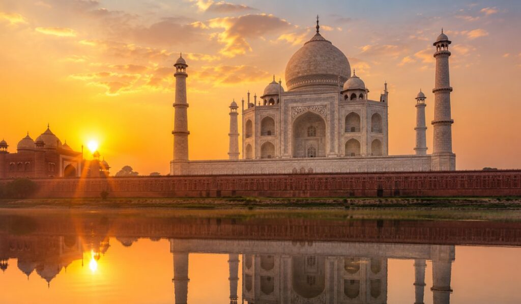 Taj Mahal at sunrise in Agra reflecting in the water with golden morning light